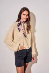 Bandana de poliéster con estampado paisley en tonos violeta, negro y blanco con detalles florales en rojo y verde.