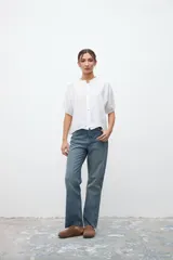 Camisa blanca de lino con cuello mao, manga corta y cierre frontal con botones.