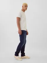 Pantalón de jean corte athletic slim, color azul oscuro con efecto lavado, de tiro medio y cierre frontal con botón y cremallera.