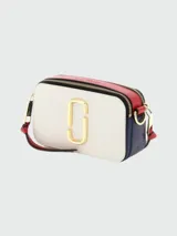 Bandolera Marc Jacobs modelo The Snapshot, de cuero color gris con detalles en beige y herrajes dorados. Presenta correa de tela con el logo de la marca y doble compartimento con cierre.