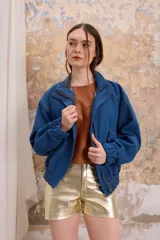 Chaqueta de jean azul con cierre y bolsillos laterales. Cuello alto y puños elastizados. Corte holgado.