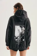 Buzo oversize negro con efecto acid wash, capucha, bolsillo canguro y mangas largas de corte raglán.