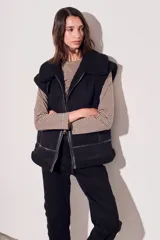 Chaleco negro con cuello de piel sintética, cierre frontal con cremallera y corte oversize.