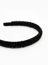 Vincha rígida de color negro, adornada con múltiples hileras de pequeñas cuentas facetadas brillantes.
