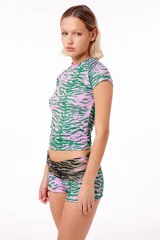 Remera anatómica de manga corta confeccionada en tejido de poliéster con elastano y estampado de tigre en tonos rosa y verde.