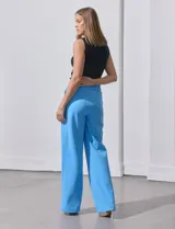 Pantalón naranja de crepe elastizado, corte recto, con bolsillos delanteros y apliques de botones metálicos.