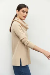 Polera de cuello alto holgado, manga larga y diseño de tejido fino con aberturas laterales en el ruedo.
