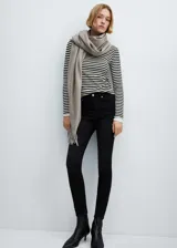 Pantalón de jean estilo skinny, de tiro alto, color negro, con cierre de cremallera y botón, y diseño de cinco bolsillos.