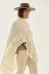 Ruana tejida en lana de cordero con diseño de sectores calados y terminación con flecos en los bordes.