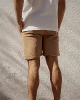 Bermuda color beige con cintura elástica ajustable con cordón, bolsillos laterales y un pequeño logo en la parte inferior de la pierna derecha.