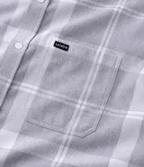 Camisa de franela de manga larga con estampado de cuadros en blanco y negro. Presenta cuello inglés, cierre frontal con botones y bolsillo en el pecho.