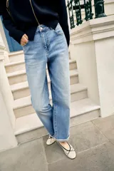 Jeans de tiro medio y corte relaxed fit, color azul con efecto deslavado, diseño de cinco bolsillos y bajo vuelto. Cuenta con cierre frontal de cremallera y botón metálico.