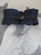 Cinto ancho tipo fajín confeccionado en cuero genuino de color negro, con diseño fruncido y hebilla metálica dorada frontal.