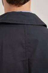 Gabardina color beige de algodón, con cuello clásico, cierre frontal con botones, dos bolsillos de ribete delanteros, bolsillo interior con botón y abertura posterior en el bajo.