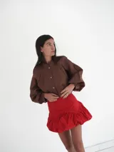 Minifalda globo de denim azul, tiro medio, con cintura limpia, cierre lateral invisible y frunces que aportan volumen y diseño abullonado.