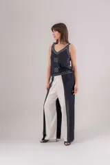 Pantalón de viscosa azul marino con cruce en las piernas tipo pareo, generando tajos laterales. Presenta bordados blancos en los bordes.