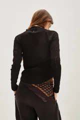 Polera negra de manga larga con diseño combinado, presentando un cuerpo de tejido liso y mangas de encaje con textura. Posee cuello alto y un ajuste entallado al cuerpo.