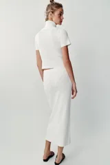 Falda midi tubo de punto color blanco, de corte recto y cintura elástica.