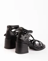 Sandalias negras de cuero con tiras cruzadas y hebillas plateadas.