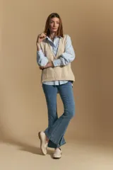 Chaleco tejido color azul, con escote en V, cierre frontal con botones y diseño de líneas verticales en relieve. Presenta terminaciones acanaladas en el ruedo y un borde ondulado en el escote.