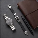 Pulsera de diseño moderno compuesta por una banda de goma negra con detalles metálicos en acero inoxidable y tres apliques circulares decorativos.