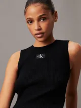 Musculosa Calvin Klein de corte slim, confeccionada en tejido de punto de canalé suave y elástico. Presenta cuello redondo, diseño sin mangas y una insignia con el monograma de la marca en el pecho.
