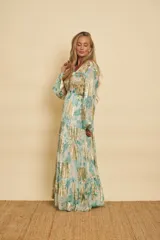 Vestido largo de manga larga con elásticos en los puños, cuello en V y diseño escalonado en la falda. Confeccionado con tela labrada que presenta estampado floral en tonos verde menta y detalles bordados con brillos dorados en el busto.