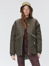 Campera reversible capitoneada con cierre frontal. Un lado es de color negro y el otro es de color beige, ambos con diseño acolchado. Cuenta con cuello redondo, mangas largas y bolsillos laterales.