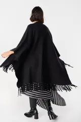 Ruana de tejido suave y envolvente en color blanco, con diseño de corte amplio y terminación de flecos en el ruedo.