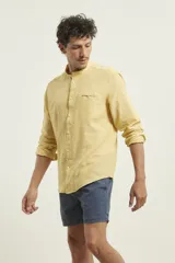 Camisa de cuello mao y manga larga, confeccionada en una mezcla de lino y algodón. Presenta un diseño de corte recto con botones en tono natural y un bolsillo pequeño en el pecho.