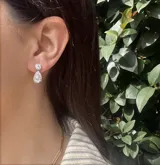 Aros pequeños con forma de gota colgante hechos en zirconia sobre base de metal plateado.