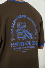 Remera oversize marrón con cuello y mangas con ribete azul. Estampado en la espalda con diseño de alfajores y texto en azul.