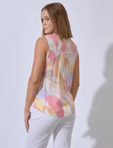 Blusa sin mangas de gasa estampada, con cuello a la base y escote en V. Presenta detalles calados en la delantera, abertura central con botones y terminación anudada.