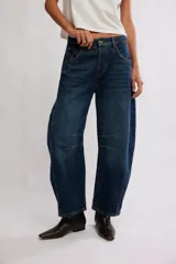 Jean de denim azul con silueta barrel y tiro medio, piernas amplias que se afinan en los tobillos, desgastes sutiles y costuras en las piernas.