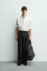 Camisa de corte regular fit confeccionada en tejido de algodón con textura. Presenta cuello abotonado, manga larga con puños abotonados y cierre frontal con botones.