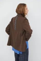Blazer de corte clásico en color marrón, con cierre frontal de un botón, solapas con muesca y bolsillos laterales. Confeccionado en tejido estructurado.