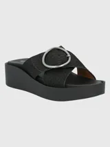 Sandalias Hush Puppies modelo Gise de plataforma y taco chino, color negro con textura efecto piel de serpiente. Capellada de cuero descarne con tiras cruzadas y una gran hebilla metálica circular plateada.