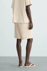 Bermuda azul marino de corte regular fit, confeccionada en tejido de algodón y lino. Cuenta con bolsillos frontales y traseros, cierre frontal con cremallera y botón.