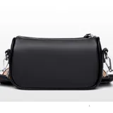 Cartera bandolera compacta de eco cuero color suela, con forma cilíndrica y correa ancha regulable de diseño rayado en tonos beige, negro y rojo.