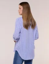 Camisa de corte clásico y silueta relajada con diseño de rayas verticales en blanco y negro. Presenta cuello camisero tradicional, cartera frontal con botones, un bolsillo aplicado en el pecho con rayas horizontales y mangas largas con sistema para arremangar.