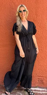 Vestido largo negro con escote en V, mangas cortas con volados, corte imperio con lazo ajustable y falda escalonada con detalles bordados.