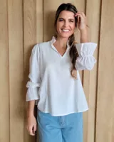 Blusa de algodón con cuello mao y volados, mangas largas con puños elásticos y corte holgado.