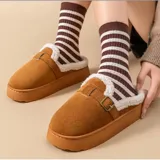 Pantuflas sin talón de gamuza marrón, con interior de corderito sintético, suela plataforma y tira ajustable con hebilla en el empeine.