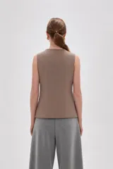Chaleco sin mangas de corte sastrero, color marrón con diseño de rayas verticales finas. Presenta cuello redondo, cierre frontal con botones y dos bolsillos laterales simulados.