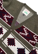 Cardigan verde con diseño geométrico en blanco y bordó, con cuello en V, cierre con botones y dos bolsillos delanteros.