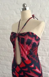 Vestido corto con estampado abstracto en tonos rojo y negro, escote halter con abertura en el pecho y corte ajustado al cuerpo.