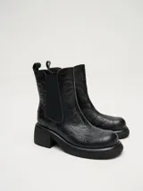 Bota tipo chelsea de cuero vacuno en color rojo con estampado floral grabado en negro. Presenta paneles laterales elásticos, suela de plataforma y taco cuadrado en color negro.
