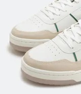 Championes urbanos de caña baja color blanco con recortes en contraste color beige y verde. Cierre con cordones y suela bicolor.
