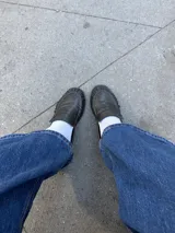 Mocasines de cuero negro con diseño clásico, punta redondeada con costuras fruncidas y tira decorativa en el empeine.
