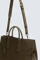 Bolso tipo bandolera de piel con acabado abatanado, diseño rectangular con doble asa de mano y detalle de llavero colgante. Cuenta con compartimento principal con cierre de mosquetón y bolsillo interior con cremallera.